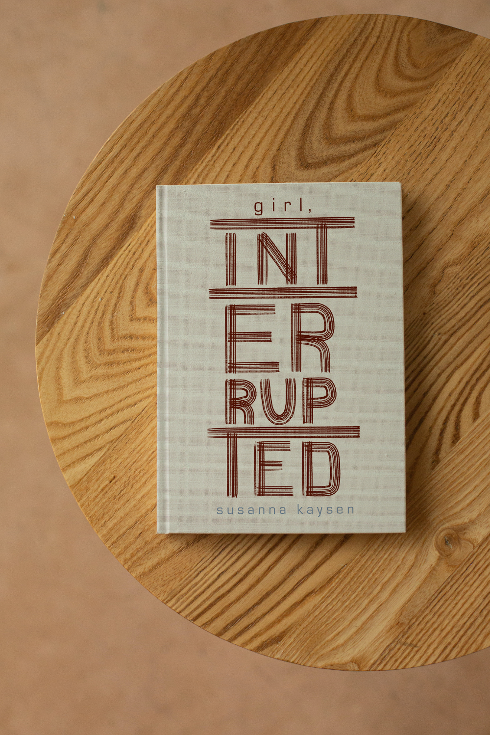 Girl, Interrupted typographic book cover mocked up on a table.